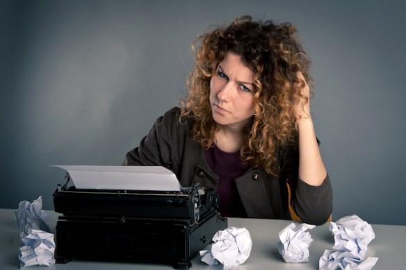 Young desperate girl writing with an old typewriter. Conceptual image.